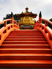 Fototapeta na wymiar Looking over red footbridge to golden pagoda