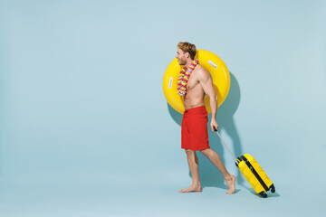 Full length side view traveler tourist man in shorts swimsuit hawaii lei hold inflatable ring...