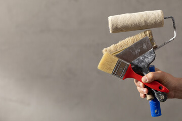 Construction worker man holding paint roller tool and concrete or plaster wall. Male hand and tools