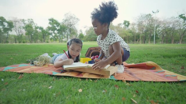 Holiday concept of 4k Resolution. Young girls are drawing pictures together in the garden.