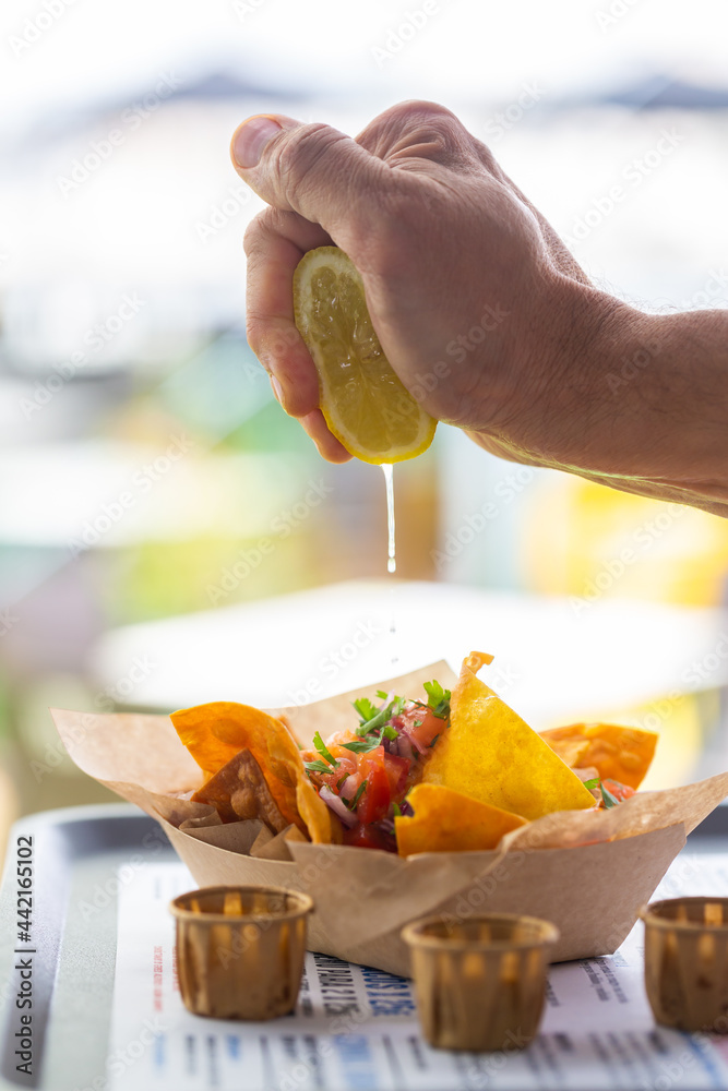 Wall mural A man's hand squeezes lemon juice into a traditional Mexican nachos buldosalsa