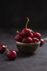Bowl with ripe juicy cherries on a dark background
