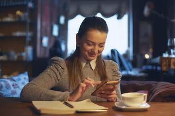 Beautiful woman sitting in a cafe at a table drinking tea and making notes in a notebook