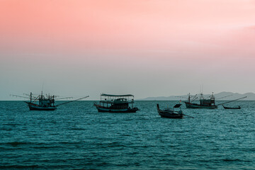 Fototapeta premium The reflection of the evening sun passes by boats moored at the seashore.