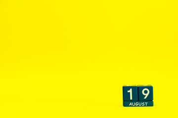 Date 19 August on blue wooden cubes on a bright yellow background with place for text
