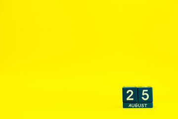 Date 25 August on blue wooden cubes on bright yellow background with place for text
