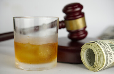 Drinking with driving offenses.Close up of glass of whisky with gavel hammer background.