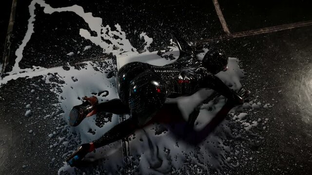 Latex fetish tight rubber suit for bdsm games on woman lying on the floor in white liquid