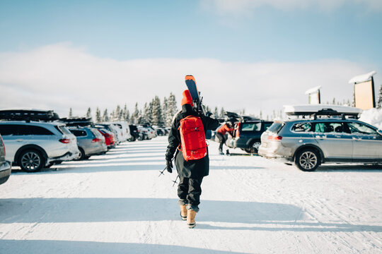 Kvinna g&aring;r med skidor p&aring; parkeringsplats