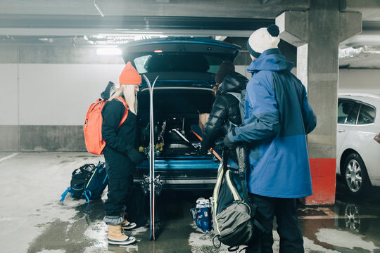 V&auml;nner packar bil i garage med skidutrustning