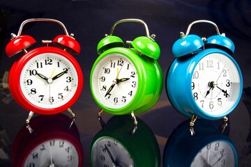 Three colorful alarm clocks on yellow background