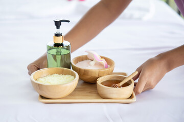 View of  Masseur  Hands Hold Spa Treatment Set with Massage oil and Sea Salt on Spa Bed