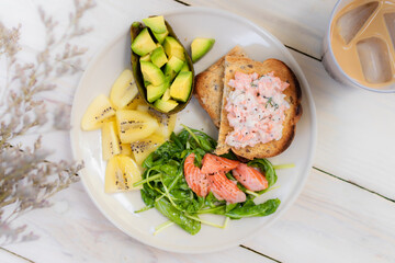 Toast salmon mayonnaise and spice  with salad, avocado and kiwi on wooden table. Healthy breakfast concept. Top view