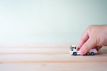 A Asian man hand holding toy white car truck in hand on gray background with copy space, Playing...