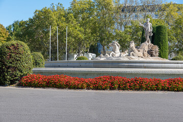 Front view of Neptune's Fountain with flowers in Madrid, Spain