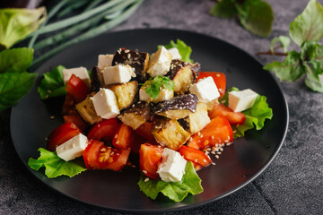 Salad with eggplants, tomatoes and feta cheese. Delicious salad on a plate