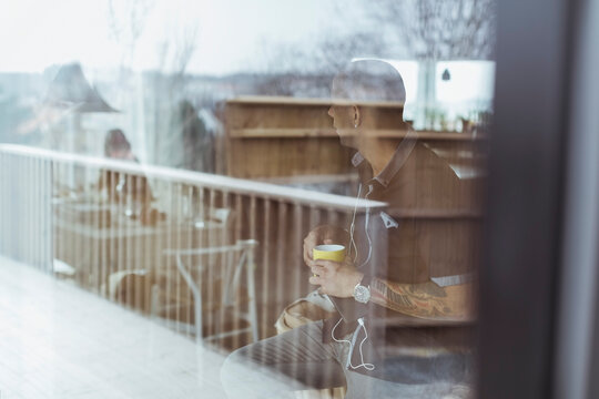 Man sitter framf&ouml;r f&ouml;nster och dricker kaffe