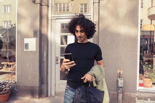 Man st&aring;r utanf&ouml;r butik och anv&auml;nder smartphone