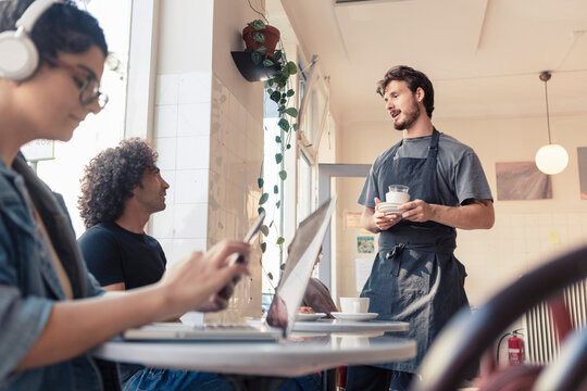 Manlig g&auml;st pratar med &auml;gare p&aring; caf&eacute;