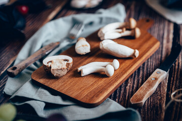 Dark photography of mushrooms, asparagus, bread, garlic and plums on a table of old wood. Vegetables recipe of for autumn or winter. Moody picture of seasonal cultivated fungus on a wooden table. - Powered by Adobe
