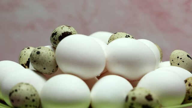 Rotating White Chicken Eggs With Quail Eggs In A Green Plate On A Pink Background.