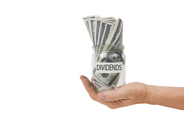 a glass jar with the inscription dividends on the label, full of hundred-dollar bills in an...