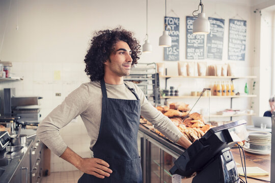 Manlig &auml;gare st&aring;r bakom kassa p&aring; caf&eacute;