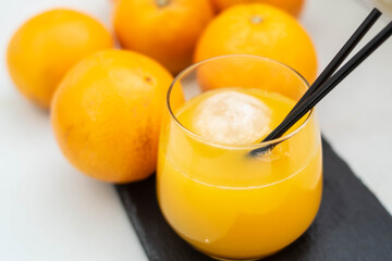 Refreshing Orange Juice whit ice and black straws on a fresh citrus blackground