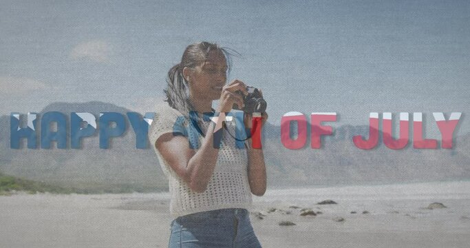 Animation of text independence day over african american woman taking photo at beach