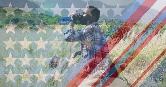 Animation of american flag over african american man drinking water in mountains