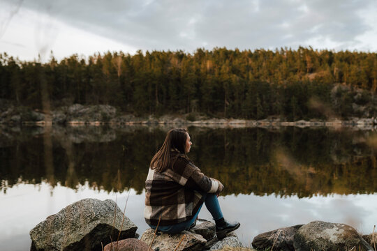 Vandrare sitter p&aring; sten vid sj&ouml; och funderar