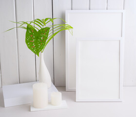 Mock uo poster frame and  palm leaves  botanical tropical house plant in beautiful white ceramic vase on white table  wall background