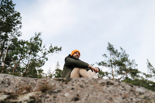 Man sitter p&aring; klippa i skog och tittar bort
