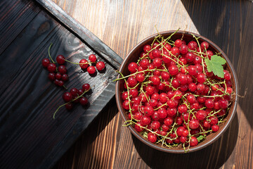 Fresh red currants in a bowl on a wooden table and berries.