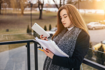 Fototapeta premium Woman sitting concrete stairs hold read use tablet pc documents contract resume for work. Lady looking for a job. Small busy business owner, copyspace. Freelancer make notes online studying 