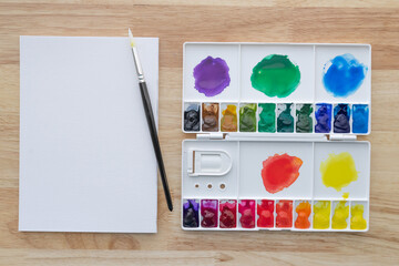 Watercolor paints set with white paper. Bright multicolored aquarelle paints for background.