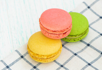 multicolored macaroon cakes on a checkered napkin. red, green, yellow macaroons. Sweet macarons on wooden background. space for text. High quality photo