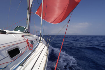 Sailboat with red spinnaker sailing downwind