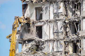 Dismantling abandoned building with mechanical excavator arm