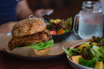 Fresh burger next to the green salad and glass cup of water.