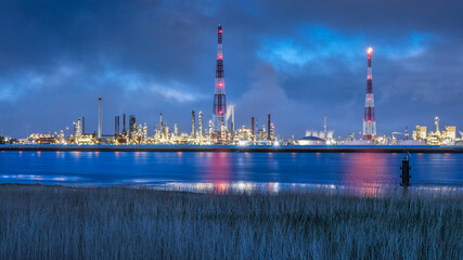 Obraz premium View on large petrochemical production plant on riverbank at twilight, Port of Antwerp