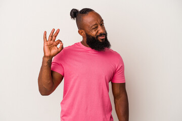 African american man with beard isolated on pink background winks an eye and holds an okay gesture with hand.