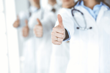 Group of modern doctors standing as a team with thumbs up in hospital office. Medical help, insurance in health care, best desease treatment and medicine concept