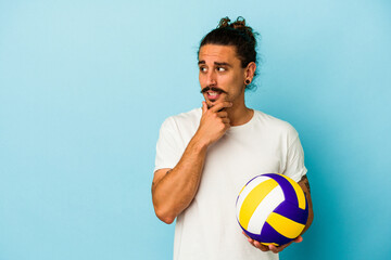 Young caucasian man with long hair isolated on blue background relaxed thinking about something looking at a copy space.