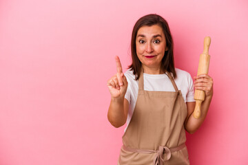 Middle age pastry chef woman isolated on pink background showing number one with finger.