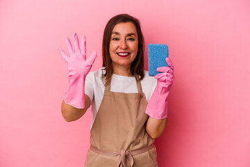 Middle age caucasian woman cleaning home isolated on pink background smiling cheerful showing number five with fingers.