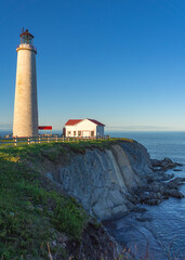 View at sunset on the Atlantic ocean, the cliffs and the Cap Des Rosiers lighthouse, the highest lighthouse in Canada, located near Forillon National Park in Quebec