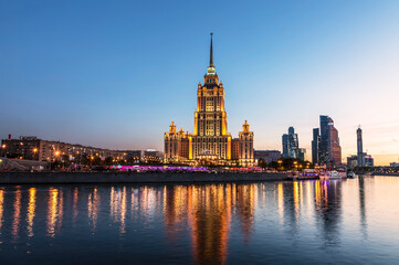 View of the Taras Shevchenko Embankment with the building of the hotel Ukraine (Radisson Royal Hotel, Moscow) and the Moscow River in the evening illumination. Moscow, Russia