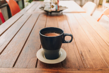 Blue mug of hot chocolate on dark wooden table in a cafe.