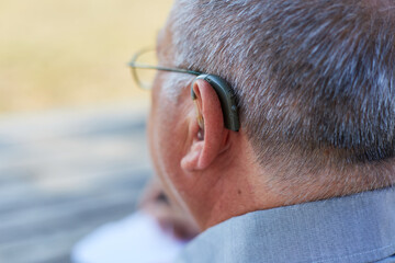 Old man back with hearing aid outdoor
